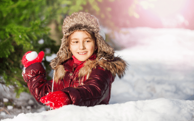 A girl in a trapper hat playing snowball