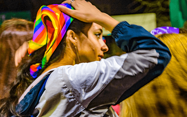 A woman is wearing a pride bandana