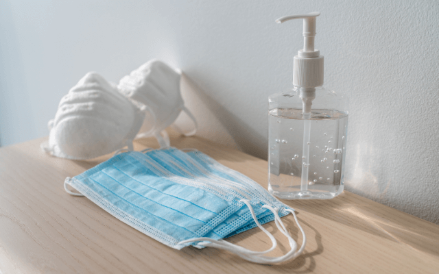 Face masks and a hand sanitizer on the wooden table