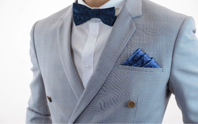 A gentleman in a grey suit, blue bow tie, and a pocket square.