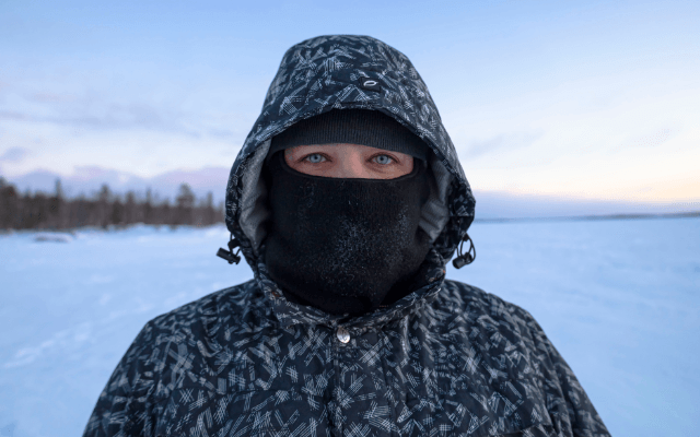 A woman in balaclava is standing in a snow covered ground