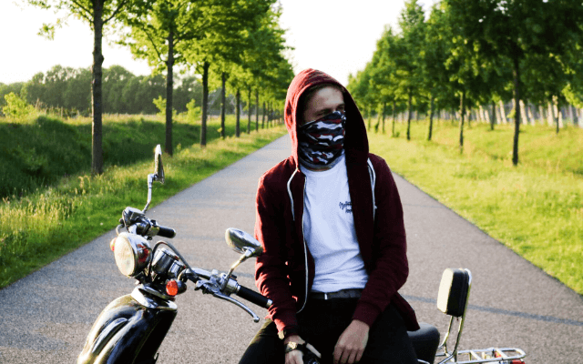 Man in camo print neck gaiter while sitting on his motorcycle